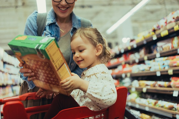 Une maman et sa petite fille qui comparent des céréales pour le petit déjeuner au supermarché